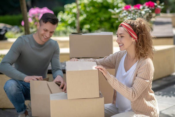 Smiling woman and her husband packing their stuff before moving - Photo, image