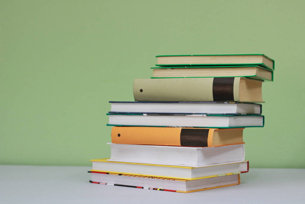 Stack of books on green background - Фото, изображение