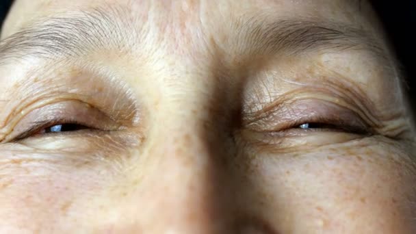Mature adult woman, caucasian ethnicity smear moisturizing cosmetic cream wrinkles on her face with fingers, looking at camera. Close-up. - Footage, Video