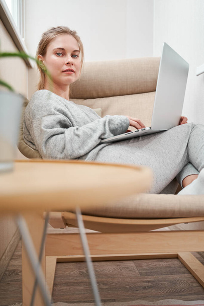 Woman in gray home suit with laptop - Zdjęcie, obraz