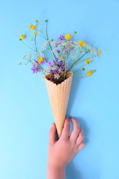 HAnd hold bouquet of wild flowers in a waffle cone. Summer concept. Flat lay. - Fotoğraf, Görsel