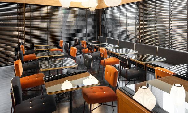 Interior decor of a retro 50s restaurant with padded chairs and empty tables and blinds on the window - 写真・画像