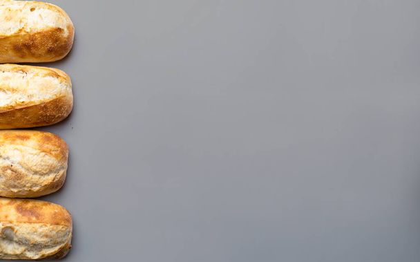 Französische Brötchen in einer Reihe auf grauem Hintergrund mit Kopierraum.  - Foto, Bild