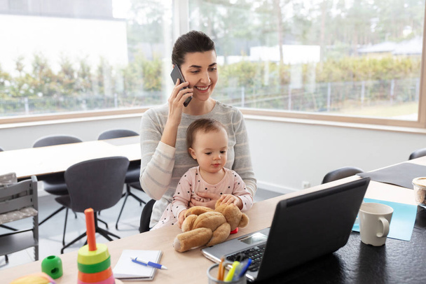 mother with baby working on laptop at home office - Foto, Bild