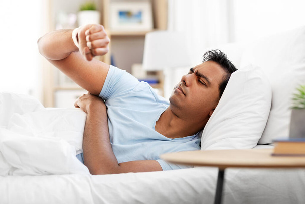 indian man in bed looking at smart watch at home - Valokuva, kuva