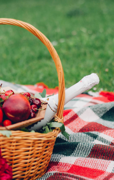 details on a picnic, glasses with red wine on a check plaid, berries and fruit glasses, books - Photo, Image