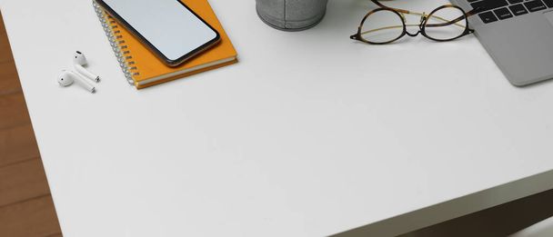 Vágott felvétel a modern irodai íróasztalról, modell okostelefonnal, irodai kellékekkel, szemüveggel és fénymásoló felülettel  - Fotó, kép