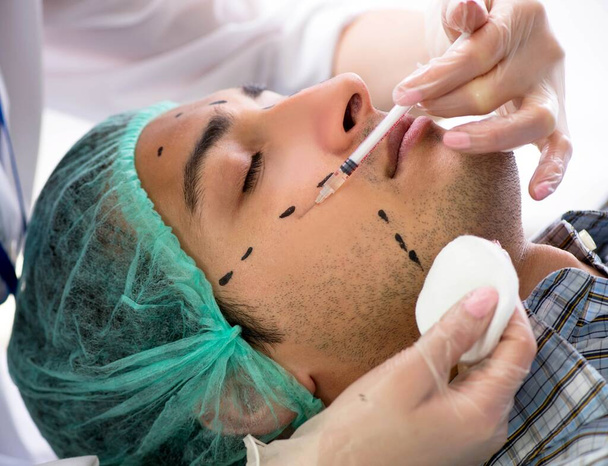 A plasztikai sebész felkészül a férfi arcon végzett műtétre - Fotó, kép