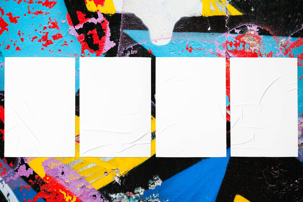 Closeup de colorido confuso pintado textura da parede urbana com quatro modelos de cartaz enrugado colado. Mockup moderno para apresentação de design com caminho de recorte. Criativa cidade urbana fundo
.  - Foto, Imagem