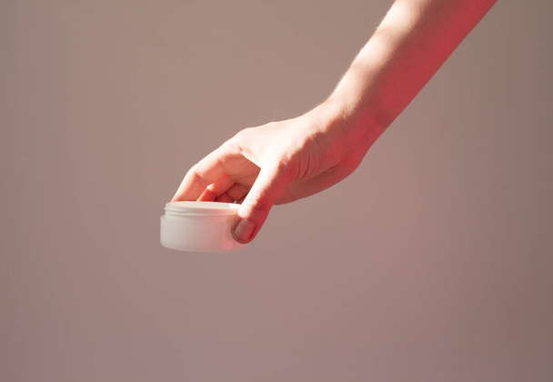  Female hand holds cosmetic product in a white tube jar, anti-aging moisturizer, eco natural cosmetics. - Valokuva, kuva