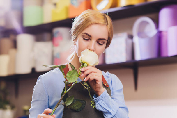 Female sales assistant working as florist and holding bouquet with customer in background. Horizontal shape, waist up. - Foto, immagini