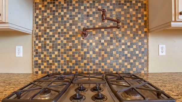 Panorama Table de cuisson et hotte d'échappement à l'intérieur de la cuisine avec robinet sur le mur de dosseret de tuiles - Photo, image