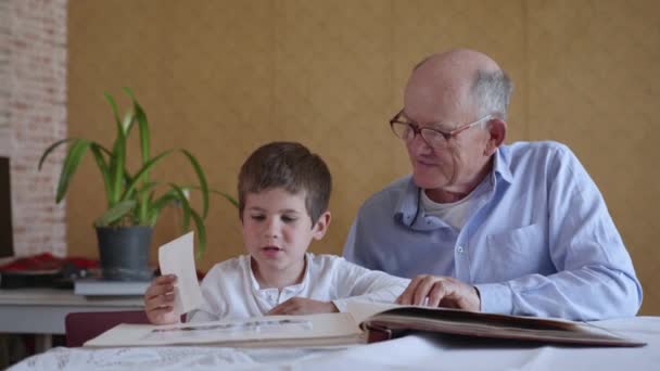 οικογενειακές αναμνήσεις, μικρό χαρούμενο παιδί με τον χαρούμενο παππού του, να βλέπει φωτογραφικό άλμπουμ - Πλάνα, βίντεο