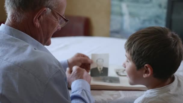 домогосподарство, добрий дід зі своєю улюбленою онукою показує фотографії своєї молодіжної радості у фотоальбомі молодості
 - Кадри, відео
