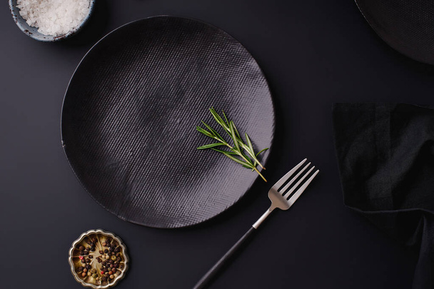 black empty plates with fork and rosemary on dark background, Dinner setting template - Foto, afbeelding