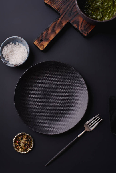 black empty plates with fork and wooden cutting board on dark background, Dinner setting template - Photo, Image