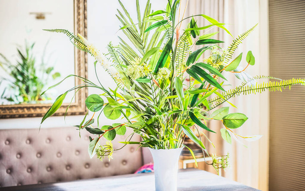 Beautiful green  bunch with various plants leaves in vase at room background. Home interior and decor - Foto, Imagem