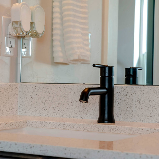 Robinet noir de culture carrée et évier sous le montage contre le comptoir blanc de la salle de bain à la maison - Photo, image