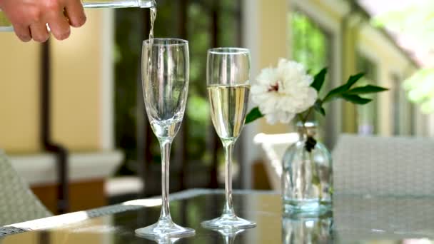 le serveur verse du champagne dans les verres. Une table dans un restaurant avec du vin et des verres sur la terrasse d'été. loisirs - Séquence, vidéo