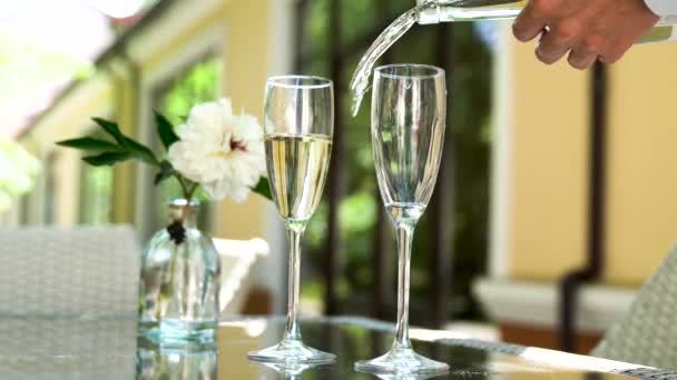 De ober giet champagne in de glazen. Een tafel in een restaurant met wijn en glazen op het zomerterras. recreatie - Video