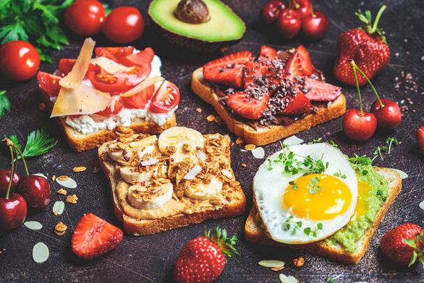 Сніданок різні тости з ягодами, сиром, яйцем і фруктами, темний фон
. - Фото, зображення