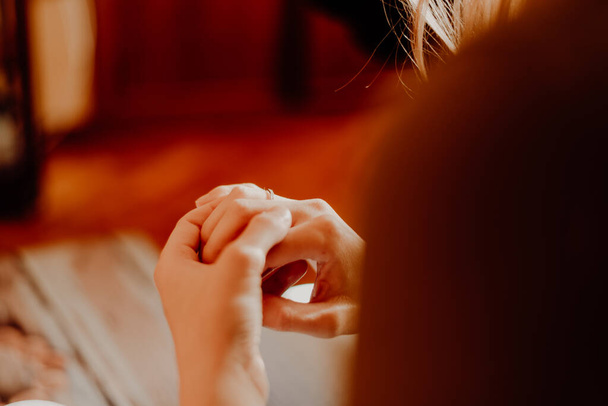 Nişan yüzüğünü sıcacık bir tonda düşünen bir kadının eli. - Fotoğraf, Görsel