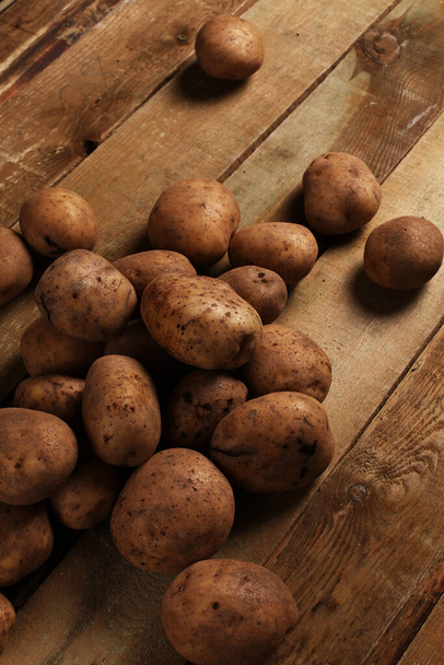 Rustieke verse ongepelde aardappelen op een houten bureau - Foto, afbeelding
