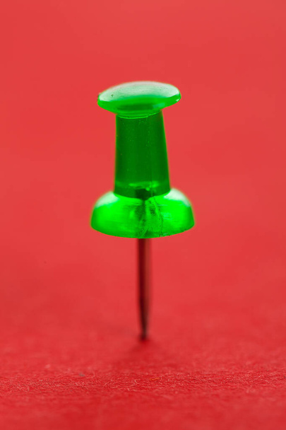Green pushpin on a red surface - Photo, Image