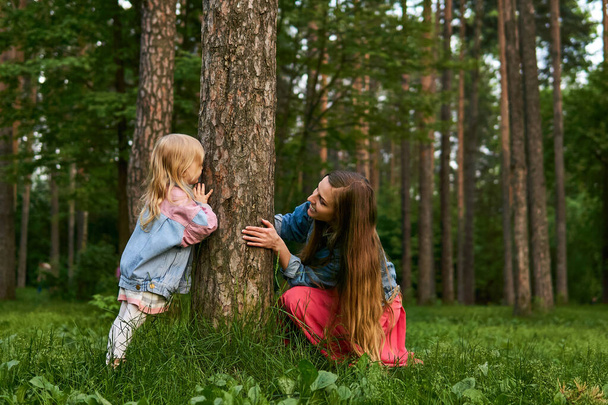 mom and toddler daughter play hide and seek and have fun in the park - Photo, Image