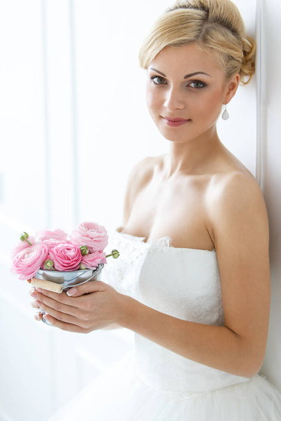 Boda. Atractiva novia sosteniendo olla con hermosas rosas
 - Foto, Imagen