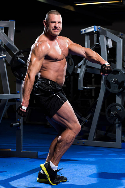 Handsome muscular man is working out in a gym - Fotoğraf, Görsel