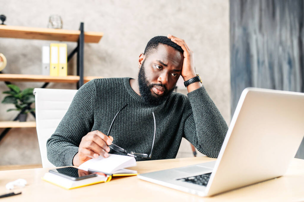 Frustrated sad black guy is watching at laptop screen - Φωτογραφία, εικόνα