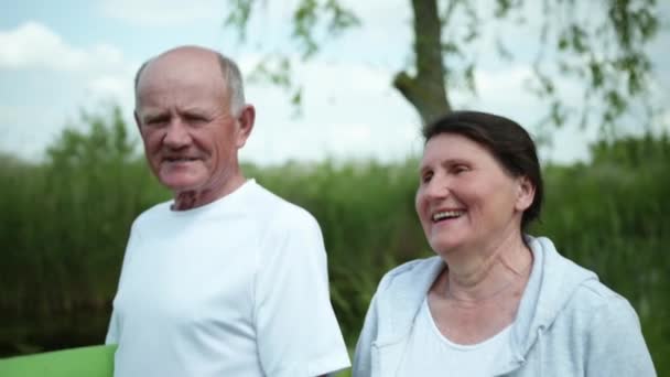 Lächelndes altes Ehepaar älterer Männer und Frauen mit einer Yogamatte oder Meditation in der Hand, nett plaudernd untereinander - Filmmaterial, Video