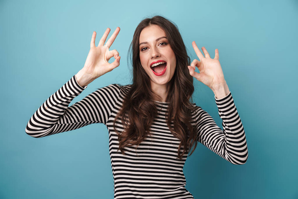 Image of excited caucasian woman smiling and gesturing ok sign isolated over blue background - Foto, imagen