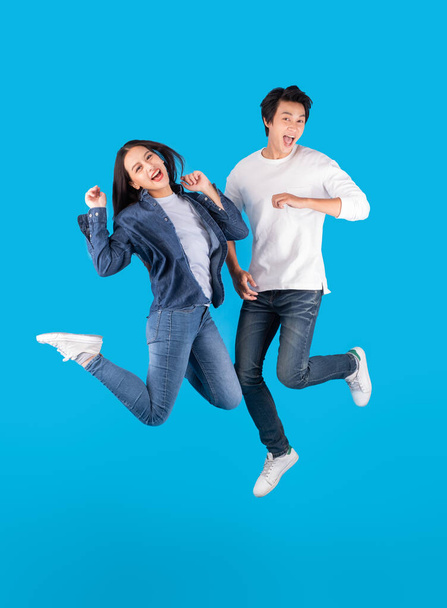 Joven pareja asiática hombre y mujer saltando con feliz y divertido sobre fondo azul
 - Foto, Imagen