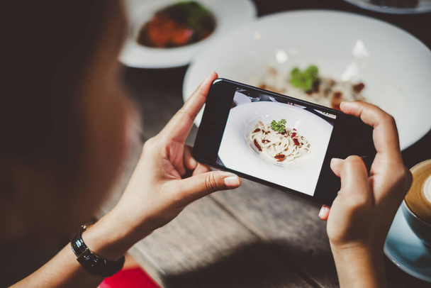 Femme utilisant le téléphone prenant des photos pour le dîner et le déjeuner repas sur la table - Photo, image