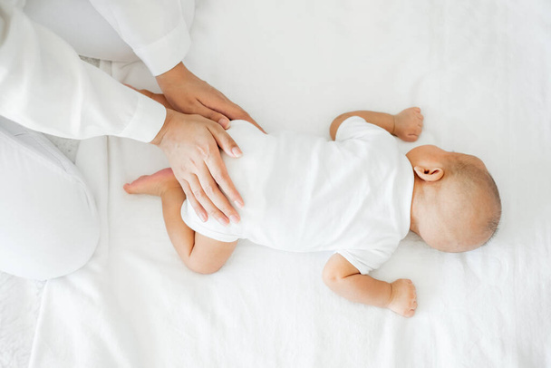 Молода азіатська мати торкається своєї новонародженої дитини з любов'ю на білому ліжку. - Фото, зображення