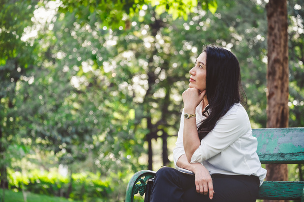 Ασιάτισσα επιχειρηματίας κάθεται και σκέφτεται στο υπαίθριο πάρκο με αντίγραφο χώρου - Φωτογραφία, εικόνα