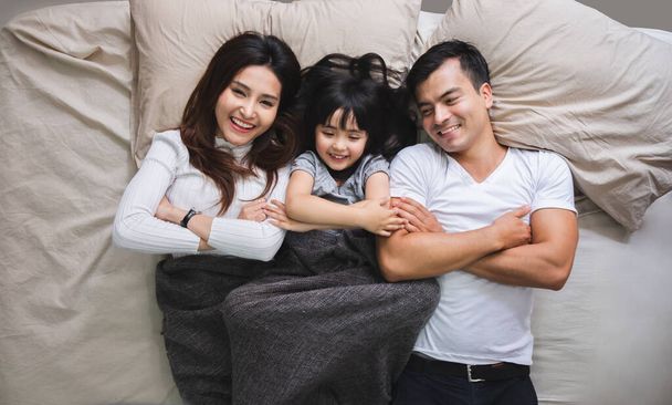 gelukkig aziatische familie liggend op bed in slaapkamer met gelukkig en glimlach, bovenaanzicht - Foto, afbeelding