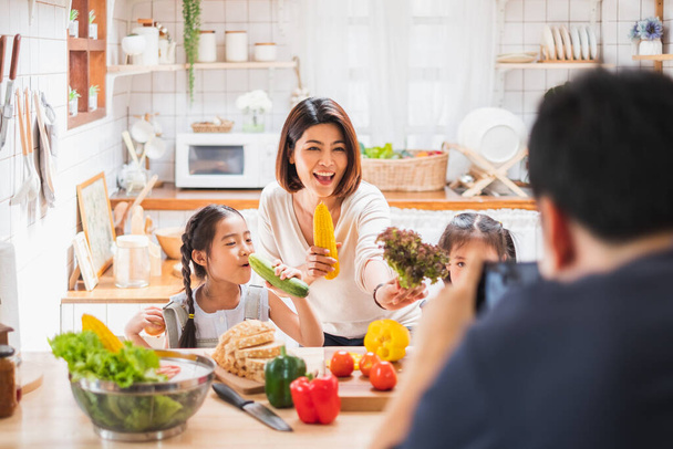 Familia asiática disfruta jugando y cocinando comida en la cocina en casa
 - Foto, Imagen