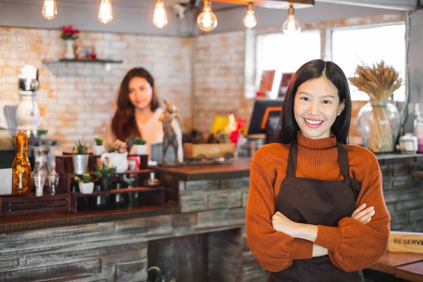 Joven mujer asiática propietaria de un negocio frente a una cafetería / bar / restaurante / cafetería y panadería - Foto, imagen