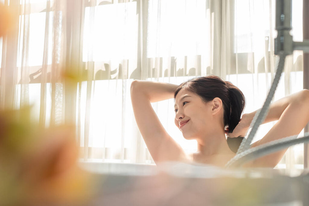 Νεαρή όμορφη Ασιάτισσα γυναίκα που κάνει μπάνιο στην μπανιέρα, κάνοντας μασάζ τέλεια περιποίηση δέρματος - Φωτογραφία, εικόνα