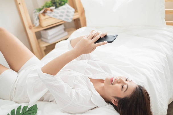 Beautiful Asian woman using laptop and smart phone in bed room for online shopping, Asian woman lifestyle concept - Photo, Image