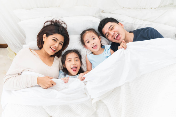 Onnellinen aasialainen perhe makaa sängyssä makuuhuoneessa onnellinen ja hymyillen, ylhäältä - Valokuva, kuva