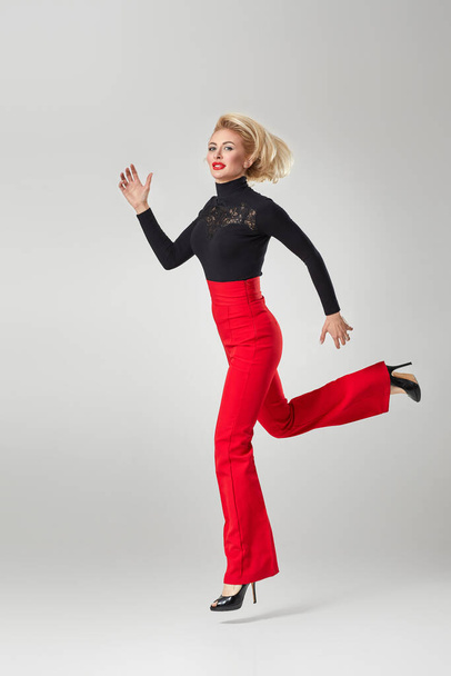 blonde woman in black shirt and red pants - Фото, зображення