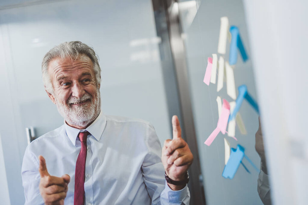 Old senior business man happy working in office, reading sticky note post it in room - Photo, Image