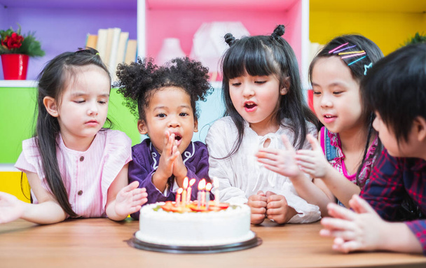 Groepsdiversiteit kinderen blazen geboortedag taart. - Foto, afbeelding
