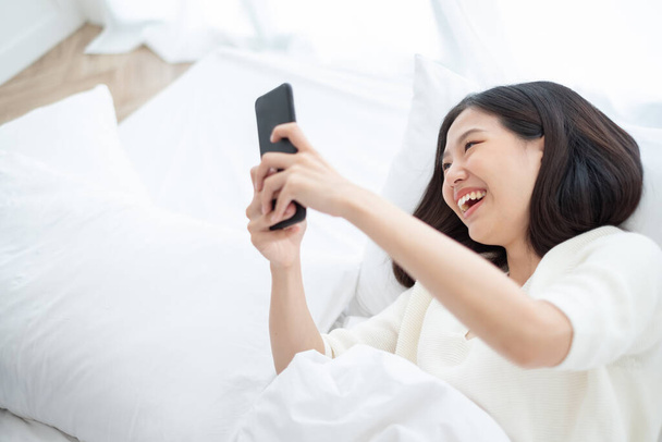 Belle femme asiatique utilisant le téléphone intelligent dans la chambre à coucher pour les achats en ligne, concept de style de vie femme asiatique - Photo, image