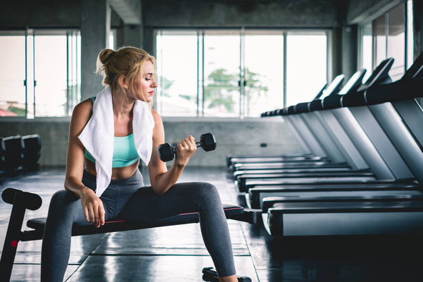 Женская тренировка, подняв гантель для силовых тренировок в спортзале - Фото, изображение