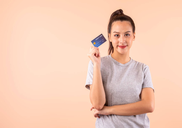 Genç Asyalı bir kadın kredi kartını elinde tutuyor. Fotokopi alanı var. Kredi kartı ödemesi nakit olmadan internet üzerinden alışveriş yapabiliyor. - Fotoğraf, Görsel